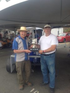 Lorne Andras (L) accepts 'The Battered Cup' on behalf of Steve Clark from Canadian motorsport legend and Hall of Famer, Bill Sadler. - VRCBC photo